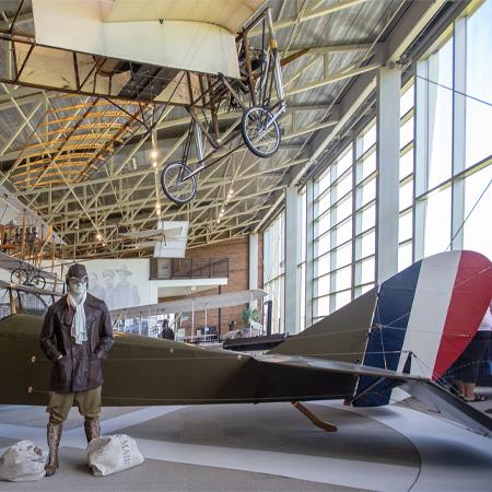 Photo of a pilot figure in front of a green plane.  