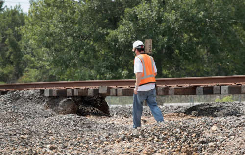 CROSBY, TX - SEPTEMBER 04: A worker walks along a section of Union Pacific railroad tracks left unsupported from flooding caused by Hurricane and Tropical Storm Harvey on September 4, 2017 in Crosby, Texas. Harvey, which made landfall north of Corpus Christi August 25, has dumped nearly 50 inches of rain causing widespread flooding in Southeast Texas.
