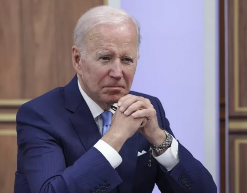 President Biden sitting down with hands clasped and stern face