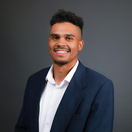 Headshot of Dr. Nicholas Chad Smith; young man smiling and wearing a navy blue suit with a white button down. 
