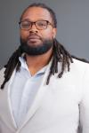 Headshot of Periloux Peay; young man in a white suit. 