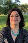 Headshot of Dr. Isbaella Alcaniz; Women smiling in front of a green field. 
