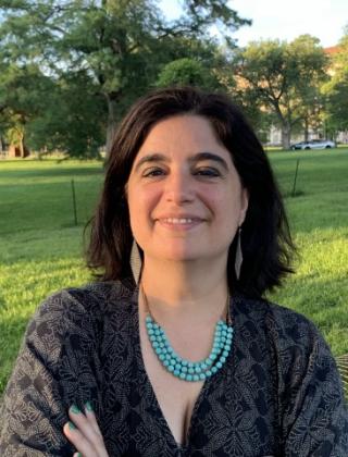 Headshot of Dr. Isbaella Alcaniz; Women smiling in front of a green field. 